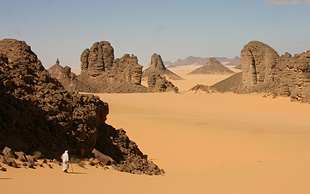 Dunkle Felskolosse, typisch für die Region Tassili N'Ajjer, erheben sich aus hellem Sand, Algerien